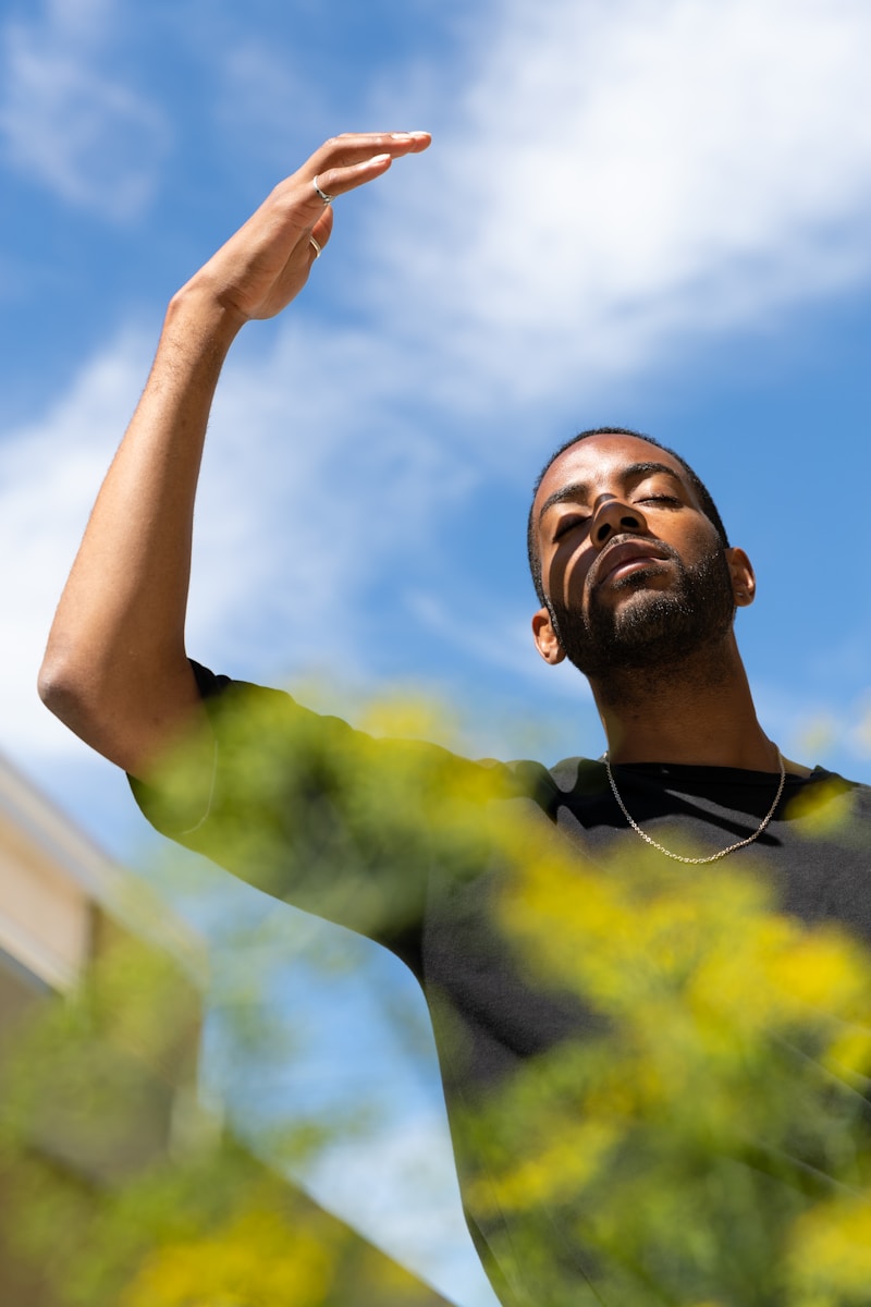 man in yellow and black crew neck shirt raising his right hand to avoid heat-related injuries